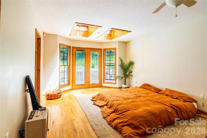 Primary bedroom boasts abundant light with skylights, the french doors lead onto back deck and 100 ft from the epic waterfall and bold creek!  