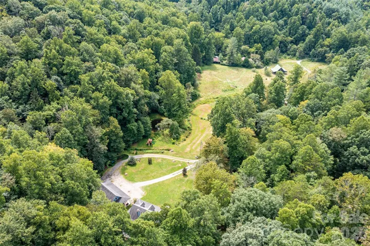 Aerial photo shows the vast 7+ acres of pasture from the home to the barn in distance