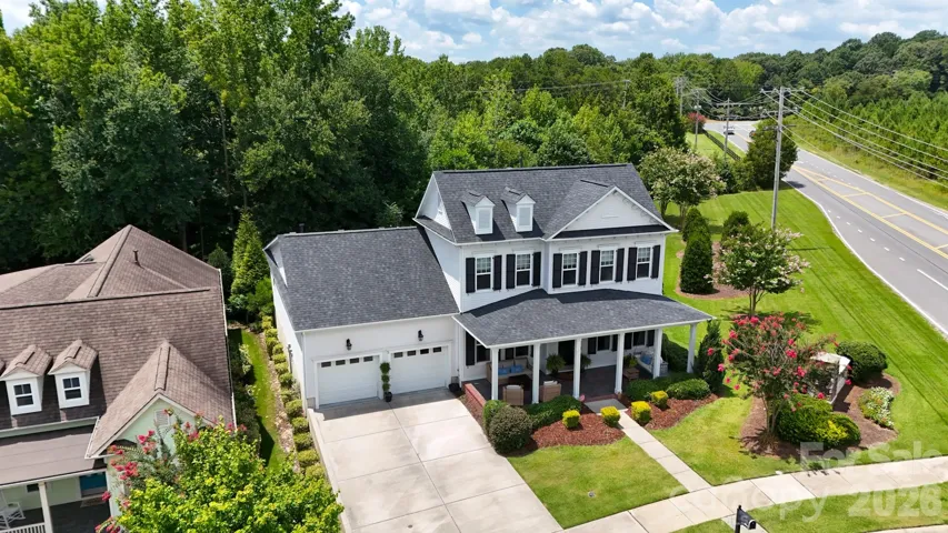 Manicured corner lot in a tree-lined subdivision, with professionally landscaped yard, neatly trimmed hedges, flowering crepe myrtles, and sculpted mulch beds.