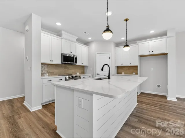 Open kitchen features 42" cabinets with soft close doors & drawers with large kitchen shiplap Island, quartz countertops, single bowl SS sink, tiled backsplash, Frigidaire gallery range appliances which are vented to outside of the home. Large walk-in pantry with solid shelving.