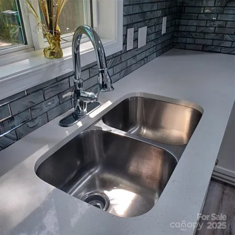 Beautifully updated kitche sink, faucet, and countertops with Glass backspash