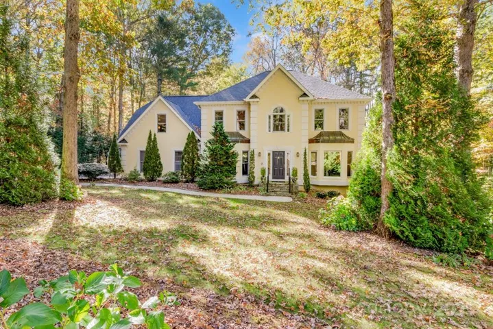 Traditional style with a nod to French Colonial, sits nobly on a wooded lot in the quiet enclave of Claremont, in Flat Rock.