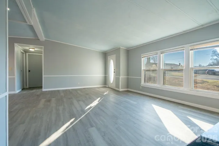 Light-filled living room with multiple windows, neutral finishes, and flexible space for a variety of furniture layouts.