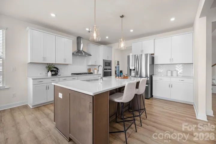 Show-stopping kitchen featuring a massive center island, gas cooktop, stainless appliances, and abundant cabinetry.
