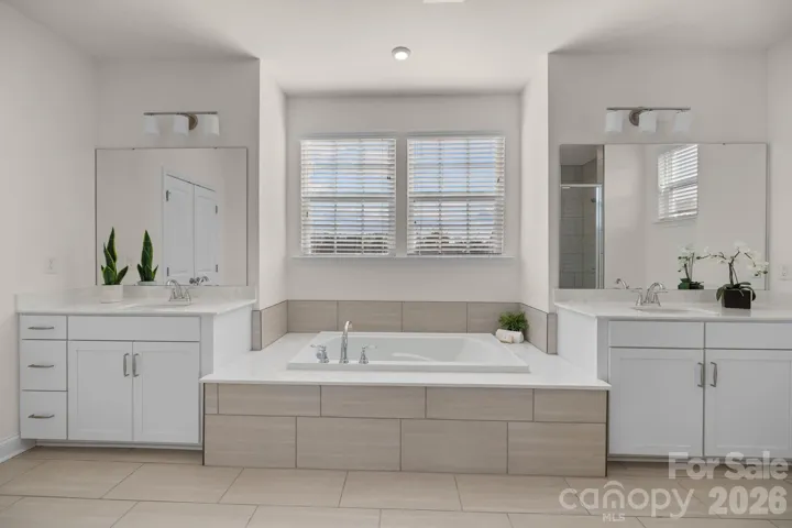 Spa-inspired primary bath features a soaking tub, dual vanities, and a large walk-in shower.
