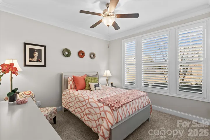 Front bedroom with crown molding, ceiling fan, plantation shutters