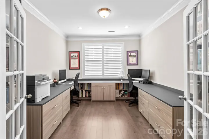Office/Flex room with built in cabinets, desks, engineered wood flooring and plantation shutters