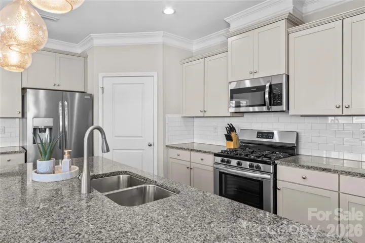Kitchen with granite countertops, 5 burner Frigidaire gas range and oven, vented microwave and french door Frigidaire refrigerator