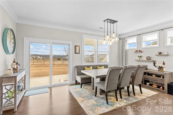 Dining are overlooking fenced rear yard with plantation shutters, designere light fixture and transom windows with shades