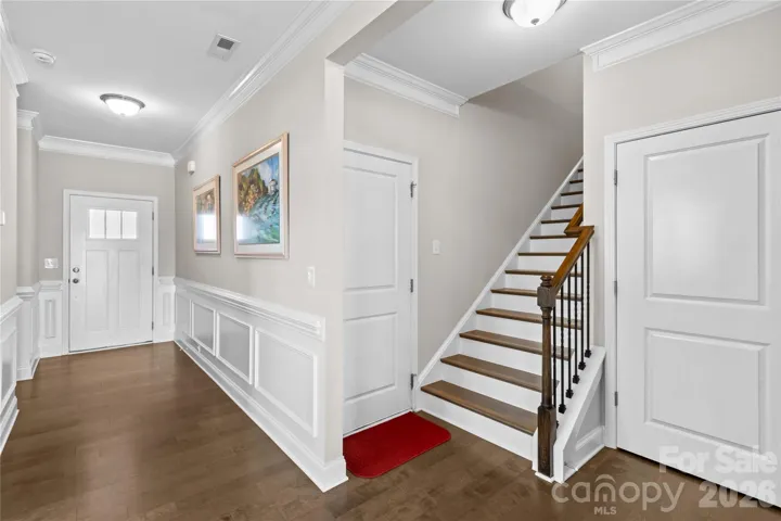 Large inviting entry with picture molding and wainscotting  Storage closets with built ins next to stairs