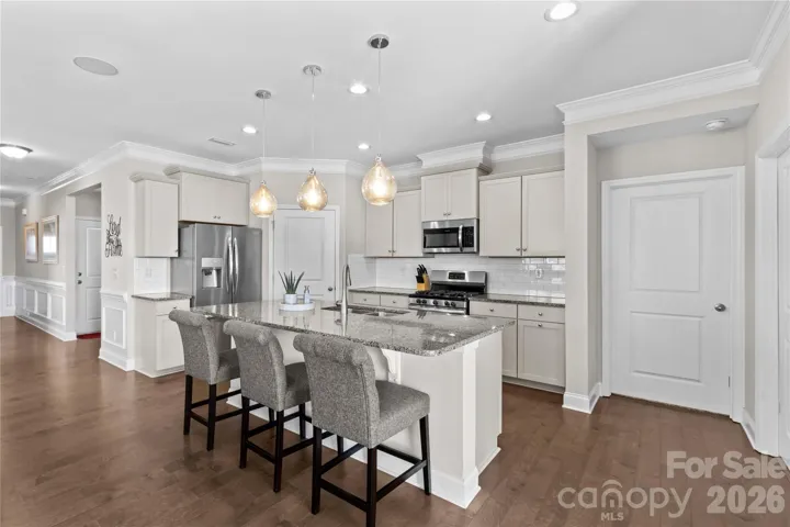 Kitchen with pendant lighting over expansive island with breakfast bar, recessed lighting and engineered flooring