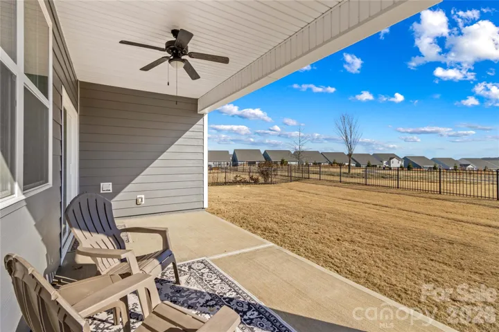 Rear yard view from covered patio with ceiling fan