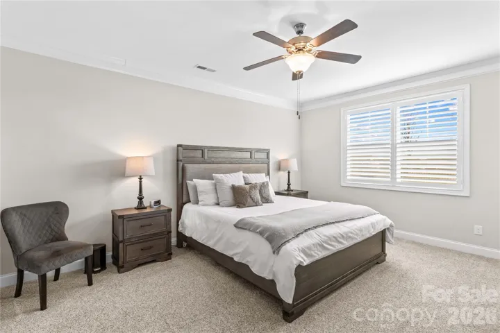 Primary bedroom with ceiling fan, plantation shutters