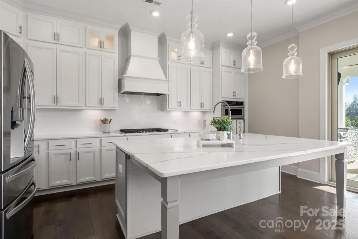 Large kitchen features stacked cabinets gas cook top and wall oven