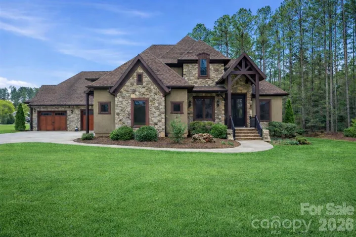 Custom home featuring stone accents, brick trim, and a dramatic covered entryway.