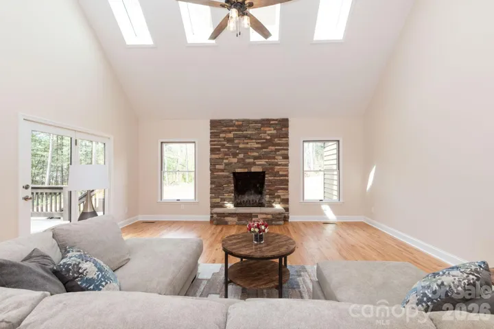 Stunning living room with vaulted ceilings, skylights, and a beautiful stone fireplace as the focal point.