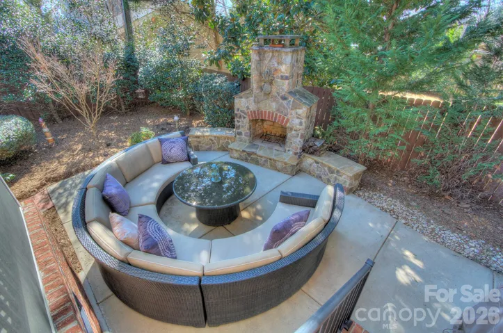 Backyard patio featuring a cozy circular seating area beside a beautiful outdoor stone fireplace.