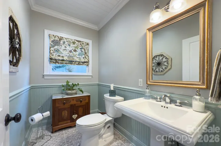 The powder room showcases charming beadboard detailing, classic fixtures and a decorative vanity area for guests.