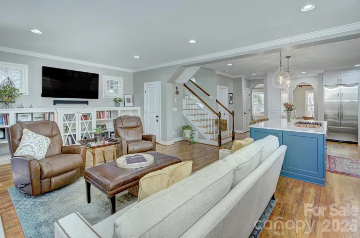 Expanded view showing the seamless connection between living area, kitchen island seating and staircase access.