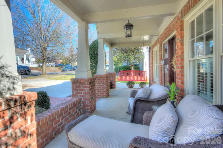 Close-up of the front façade showcasing detailed brickwork, arched porch entry, and cozy seating areas.