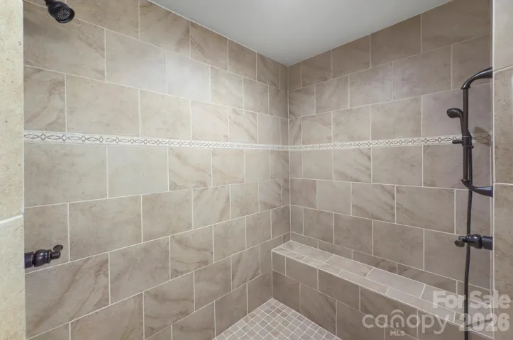 Oversized tiled shower with built-in bench offers a spa-like experience.