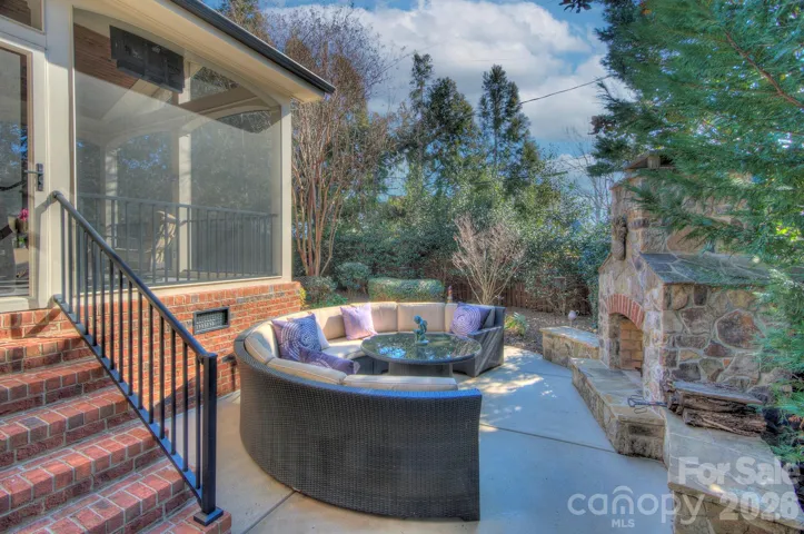 Backyard patio featuring a cozy circular seating area beside a beautiful outdoor stone fireplace.