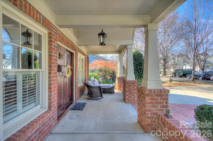 Covered front porch offering comfortable lounging spaces and a perfect spot to enjoy the neighborhood setting.
