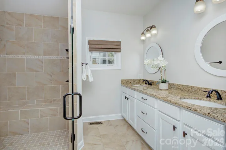 Well-appointed primary bath features dual vanities, granite countertops, and abundant storage.