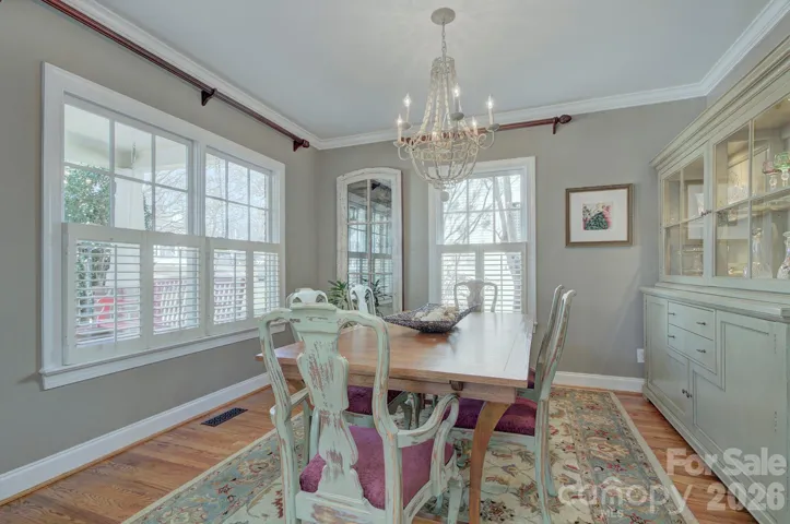 Light-filled formal dining room with elegant chandelier, large windows, and beautiful built-in cabinetry creates a welcoming space for gatherings.