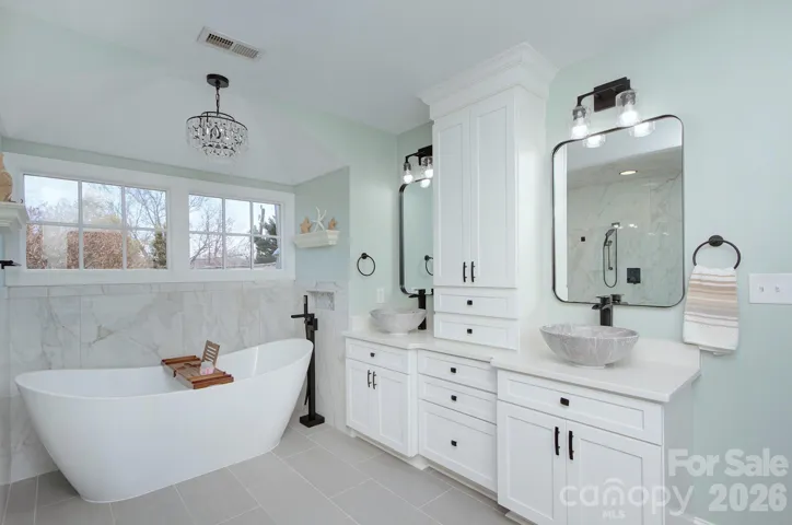 Dual vessel sinks and custom cabinetry provide both style and functionality in this beautifully updated primary bath.