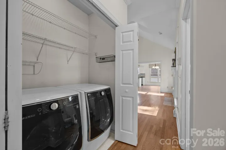 The home features a cleverly designed functional laundry closet and includes shelving for supplies, all behind a discrete set of doors that maintain the peace and elegance of the private primary suite area.