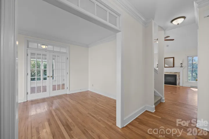 The living room, situated immediately to the left as you step inside, is a space defined by its airy and light-filled ambiance with the main opening into the room elegantly accented by a transom.