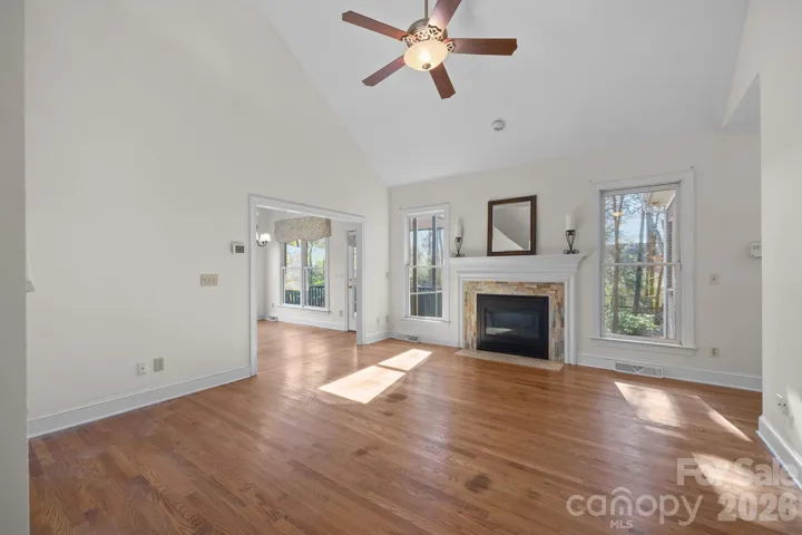  The room is anchored by a stunning fireplace, which features an elegant tiled stone surround that adds texture and a focal point to the space.  The drama of a vaulted ceiling creates an expansive, airy feel, while a centrally mounted ceiling fan ensures comfort and airflow year-round. 