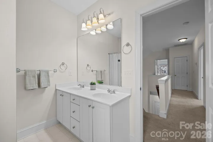 It features a practical and efficient setup with a dual vanity, which provides two separate sinks and ample counter space for shared use, complete with dedicated storage below. For bathing, the room includes a classic shower/tub combination.