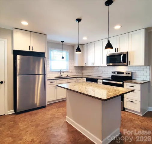 Pretty kitchen has stainless steel appliances, granite counters, white shaker cabinets!
