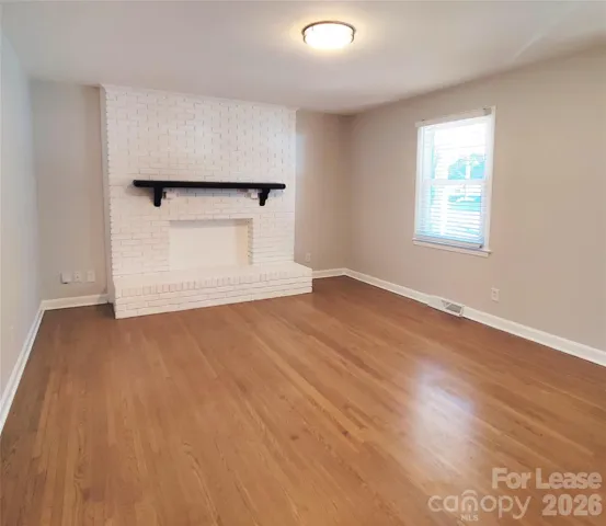 Family room has gorgeous hardwood floors and pretty decorative fireplace. 