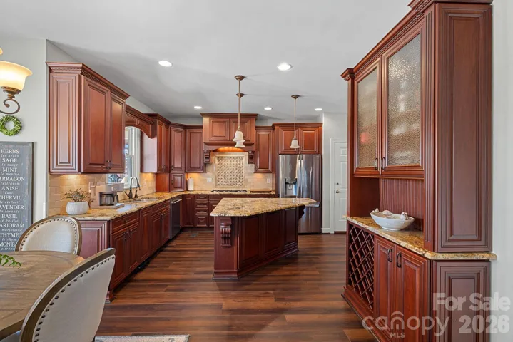 Notice the custom cabinetry, pull up bar stool island and the additional credenza for serving and entertaining guests.