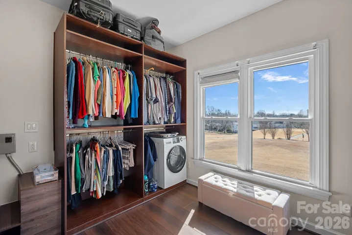 Primary walk in closet showing the newly installed washer/dryer, steam shower hook ups,custom cabinetry, and a Golf Course view.