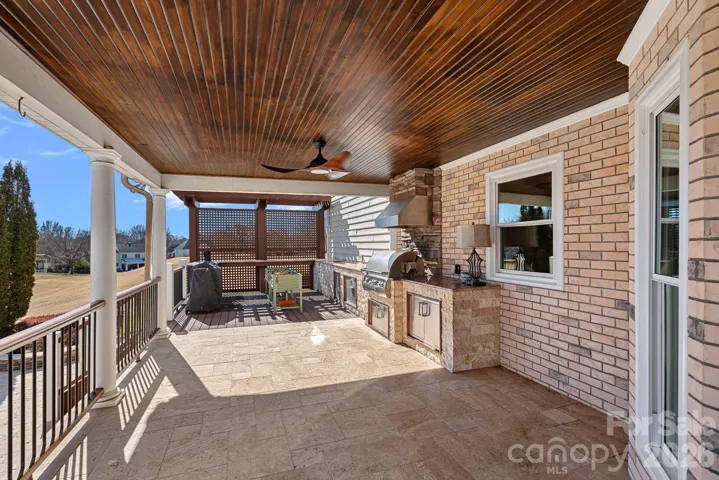 Adjacent to the outdoor covered living space is also an outdoor kitchen grilling station with gas grill and venting hood.