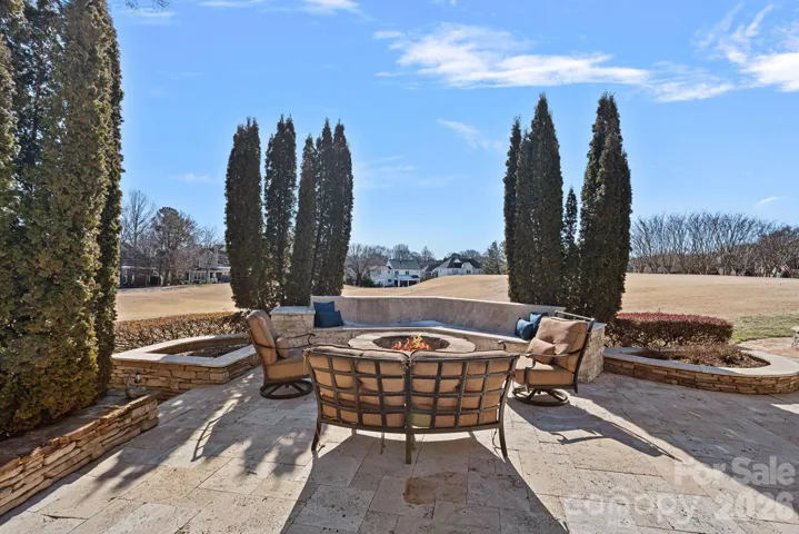 Outdoor firepit area with stone beds for planting beautiful flowers and long Golf Course views.