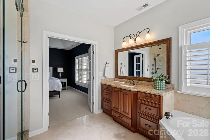 Primary Suite Bathroom features gentleman height counters, garden tub, custom tiled walk in shower with glass fronts, and tiled flooring.