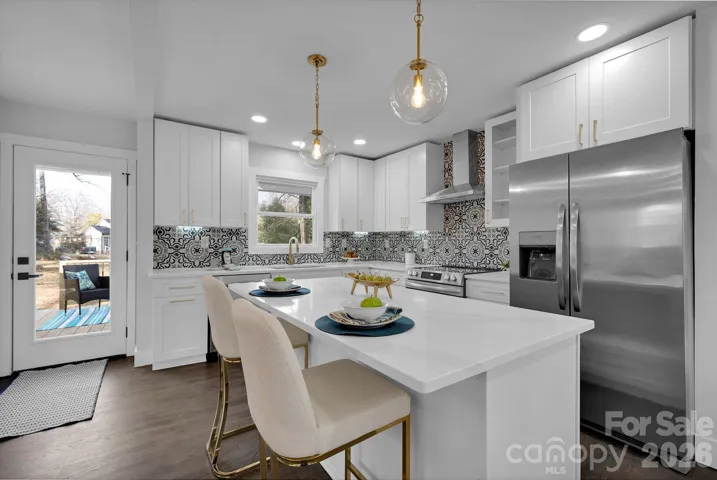 Kitchen – Fully renovated kitchen featuring white shaker cabinetry, quartz countertops, stainless steel appliances, and a striking patterned tile backsplash.