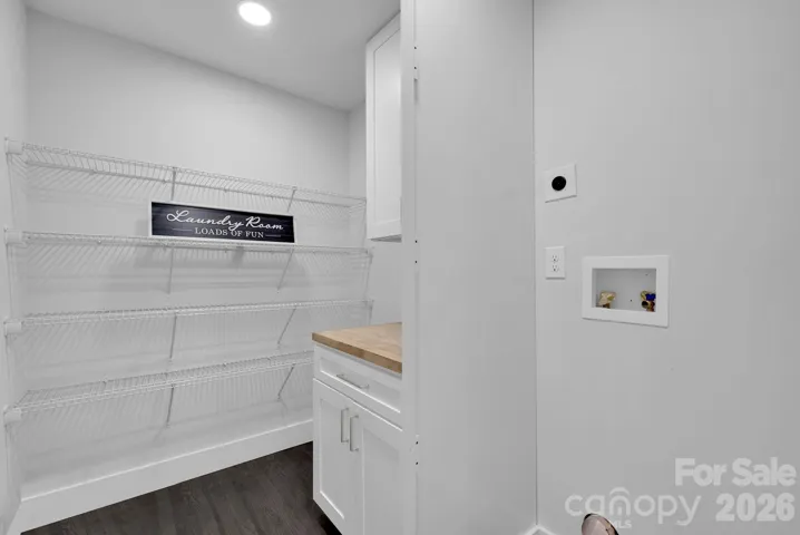 Laundry Room – Dedicated laundry space with built-in cabinetry, countertop workspace, and open shelving for convenient organization.