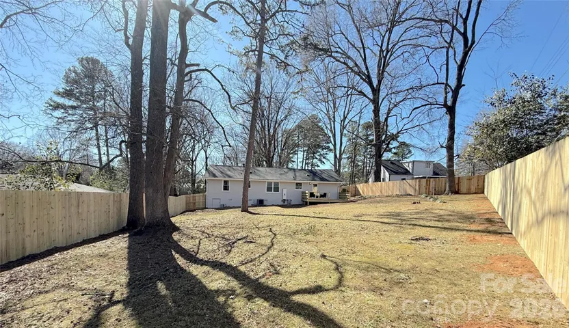 Backyard (Full Lot View) – Deep, open lawn bordered by fencing and mature trees, offering flexibility for recreation or future additions.
