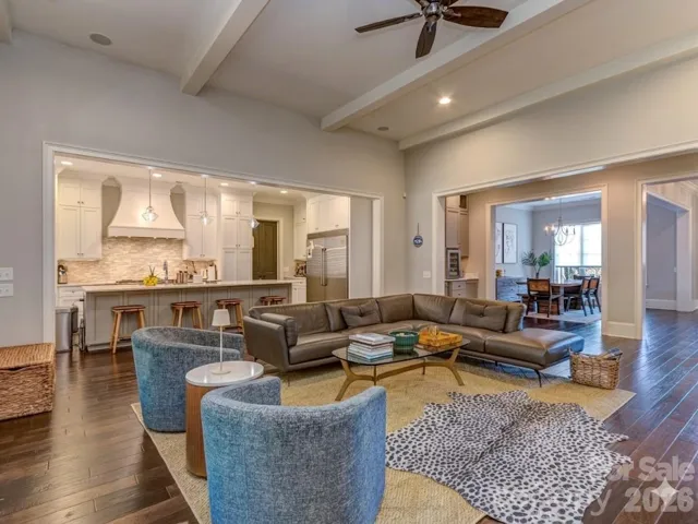 The Open Great Room Features Coffered Ceiling, Wood Floors, Shiplap Entertainment Wall, Gas Log Fireplace, & Access to the Screened Porch & Gourmet Kitchen