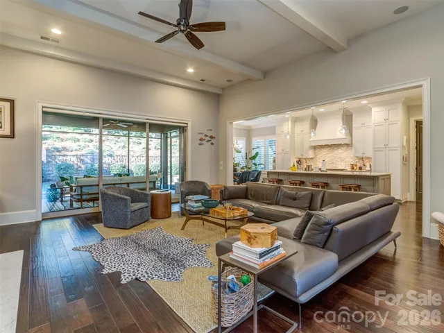 The Open Great Room Features Coffered Ceiling, Wood Floors, Shiplap Entertainment Wall, Gas Log Fireplace, & Access to the Screened Porch & Gourmet Kitchen