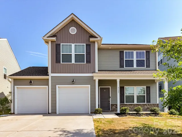 Charming two-story home with inviting covered front porch, two-car garage, and attractive curb appeal, nestled in a well-maintained neighborhood.