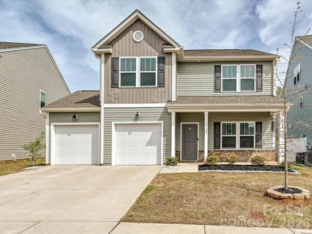 Charming two-story home with inviting covered front porch, two-car garage, and attractive curb appeal, nestled in a well-maintained neighborhood.