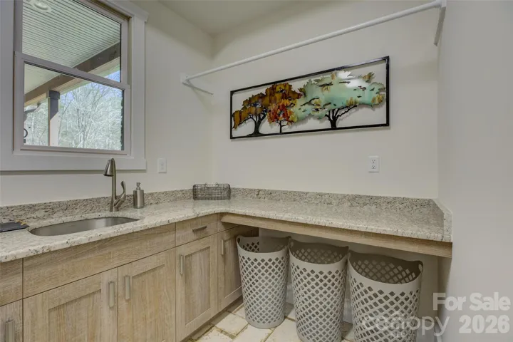 Main floor laundry room with tile floor, sink, and lots of cabinets.