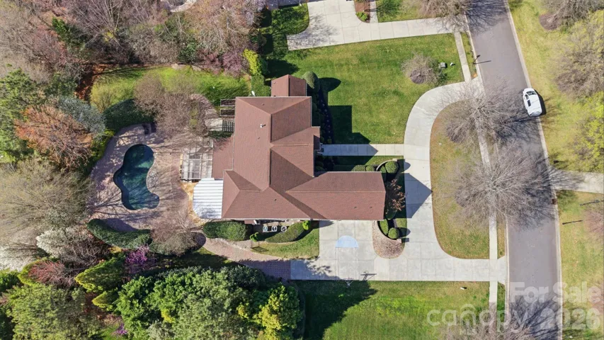 Aerial view showcasing the estate’s expansive homesite, circular driveway, and private backyard retreat complete with resort-style pool and extensive paver patio.